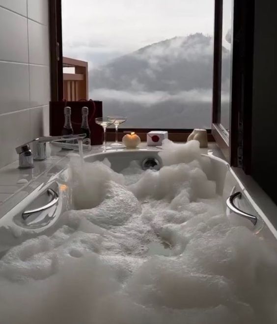 Bathtub with a window outlooking clouds