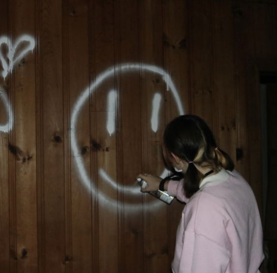 girl spray painting a smiley face